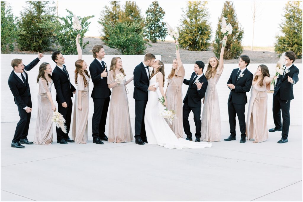 modern and classic winter wedding party photo! "everyone cheers the bride and groom on as they kiss!"