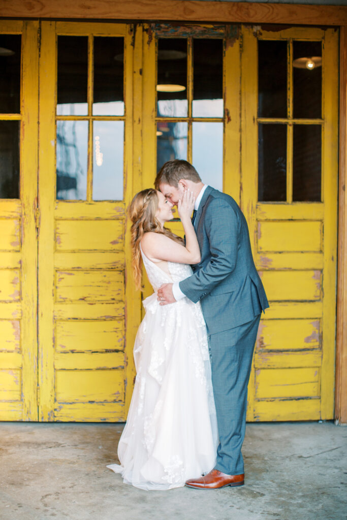 Couple poses in front of the yellow doors of the standard knoxville wedding venue after their ceremony downtown